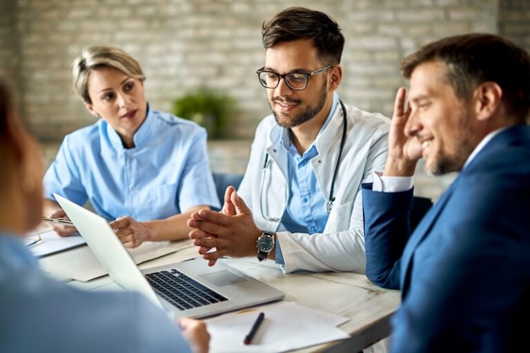 RealTime Services - Group of healthcare workers and businessman using laptop while having a meeting in the office